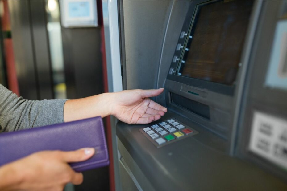 tangan seseorang sedang mengambil uang di ATM
