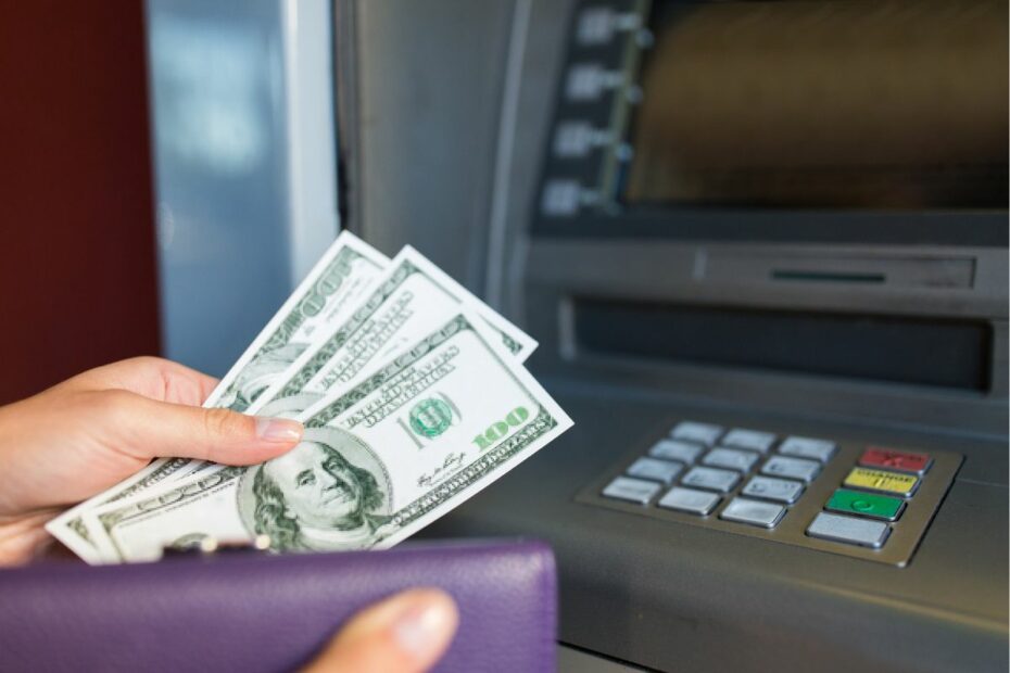Seseorang mengeluarkan uang dari dompet untuk disetor tunai melalui ATM.